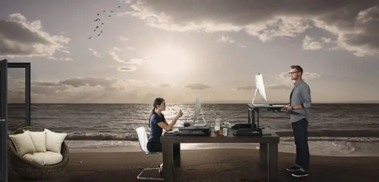 A man and woman sitting at a desk with a laptop, working together on a project