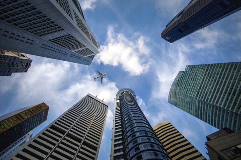 An airplane soaring above a city skyline with towering buildings