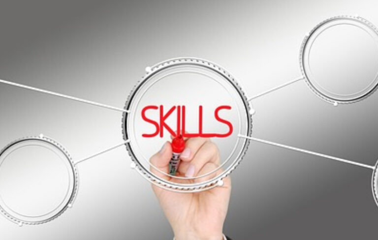 A person is pointing to the word skills on a grey background