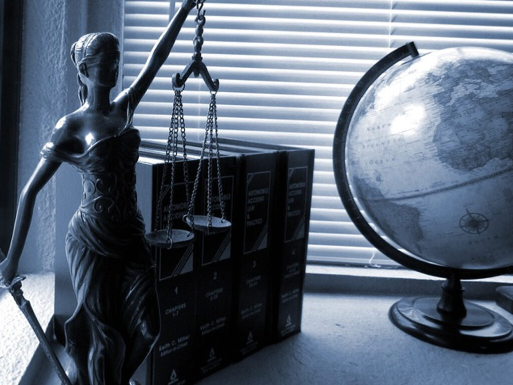 A globe resting on books, with a statue of a lawyer beside it